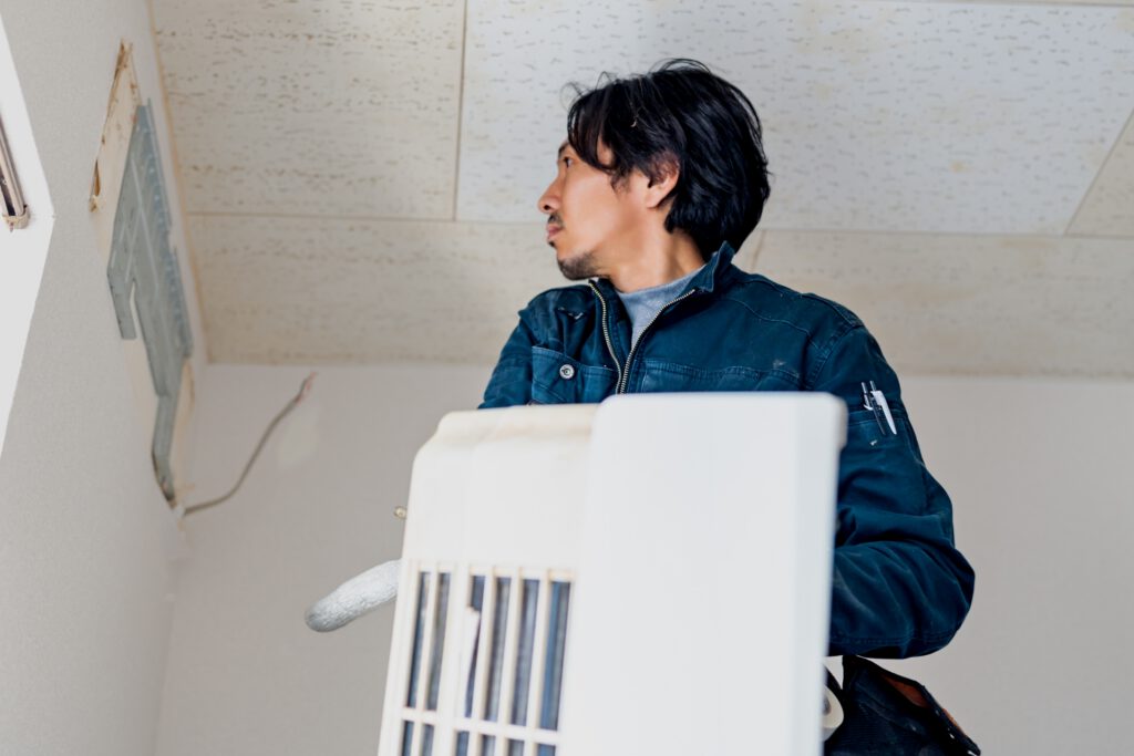 エアコンを取り外す作業員